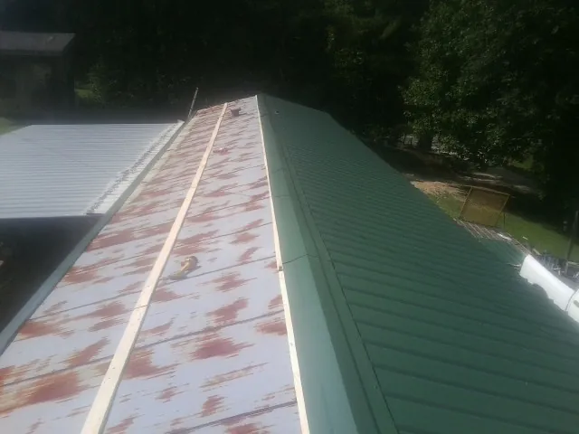 Old rusted panels beside newly installed green metal roofing — Wind Damage Roof Repair by Roofing Brothers in Patuxent River