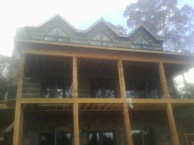 Dormers and porch framing on a large log home under construction — Roof Coating work by our crew in Patuxent River