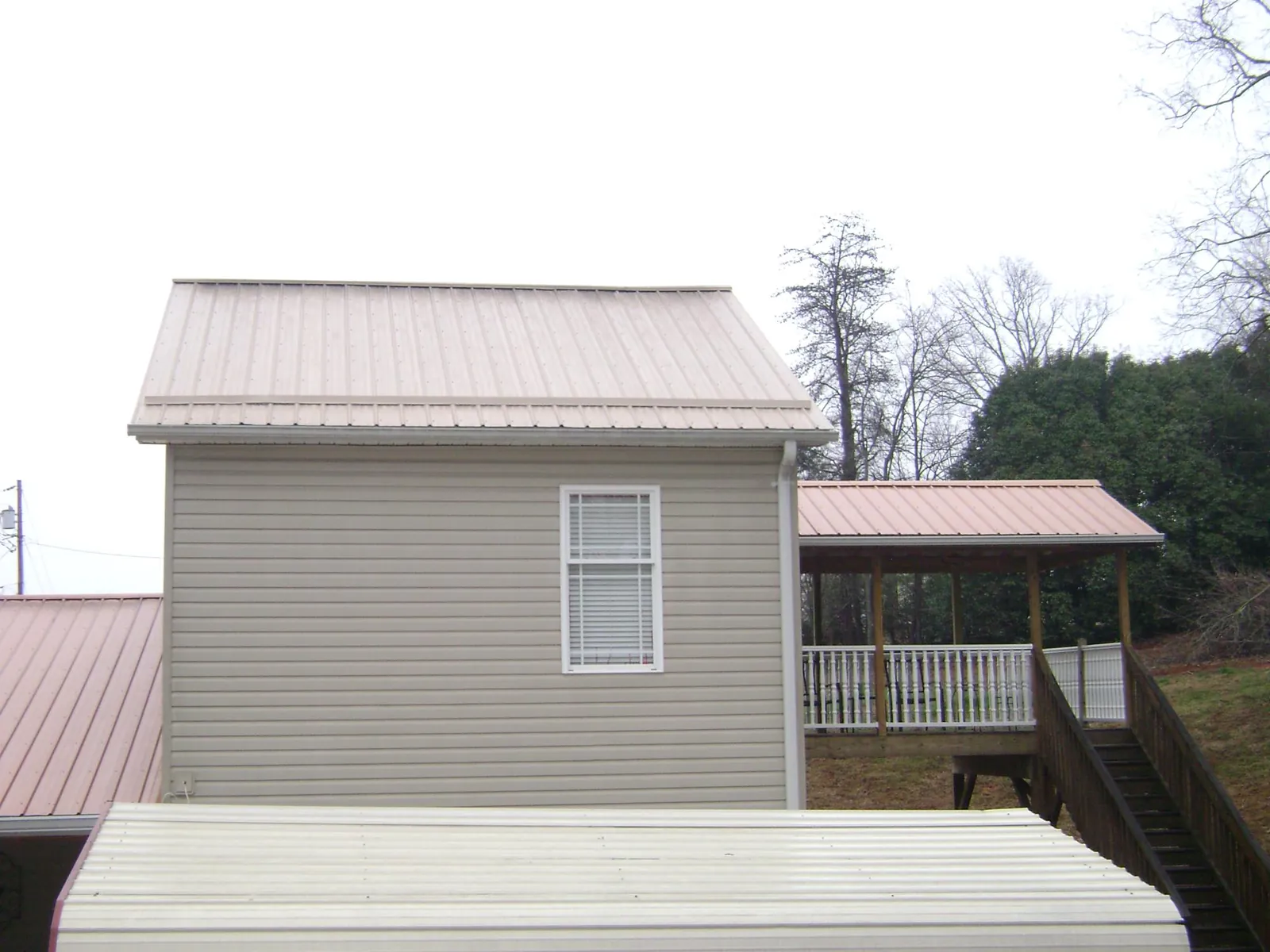 Tan metal roofs on a two story addition and attached porch, from a Roof Replacement job in Patuxent River