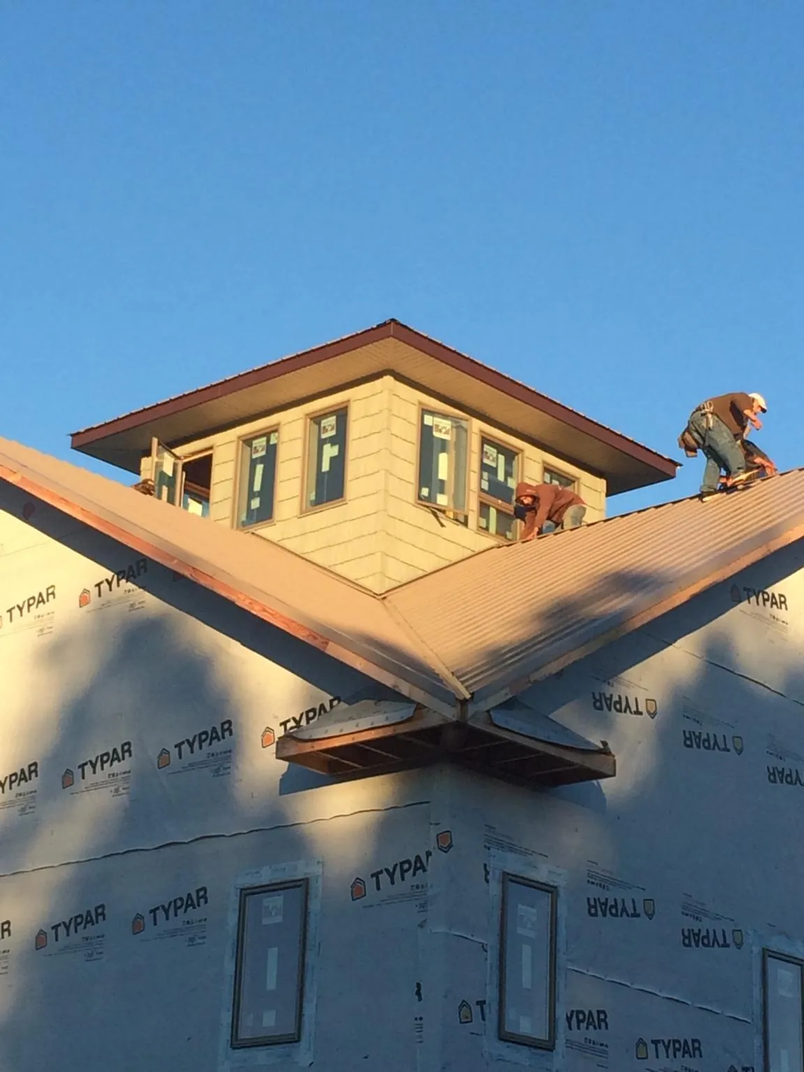 Roofers working around a rooftop cupola on a new metal roof at sunset — Roof Waterproofing in Patuxent River by Roofing Brothers
